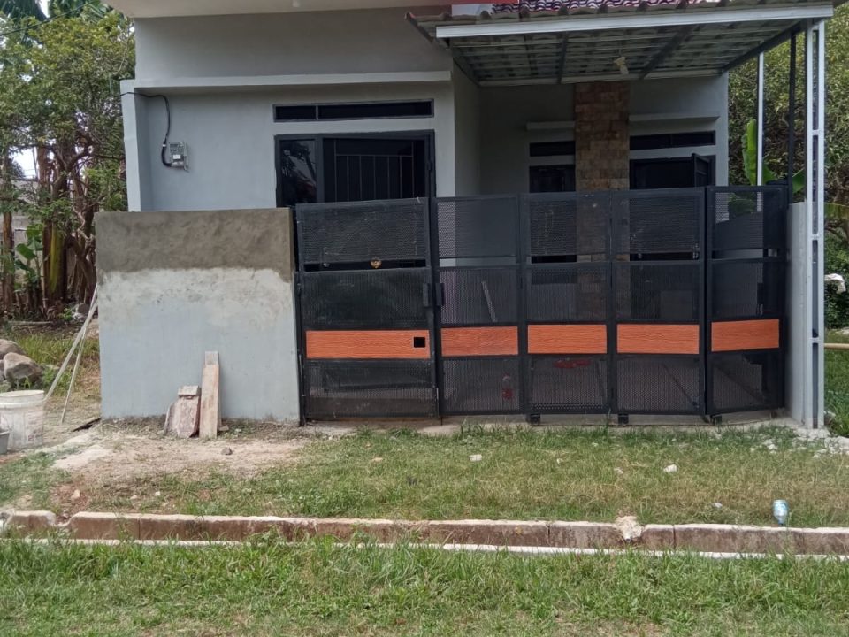 Foto rumah satu lantai di lokasi dengan pagar besi hitam dan carport